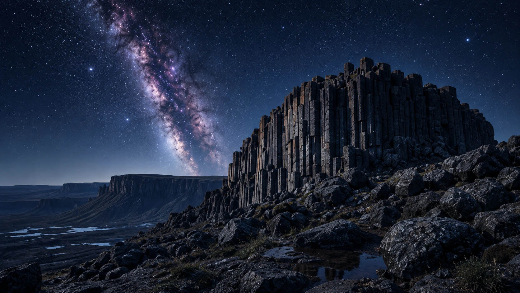 Weathered basalt columns rising from a vast nocturnal plateau beneath the Milky Way.